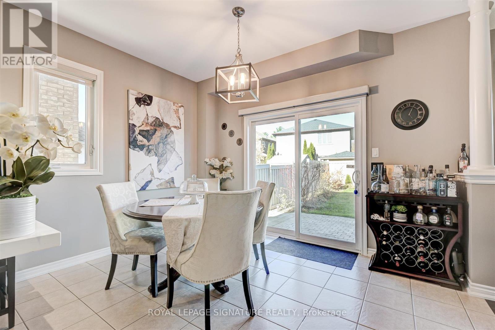 A dining room with a table set for two and a view of the backyard through the sliding glass door.