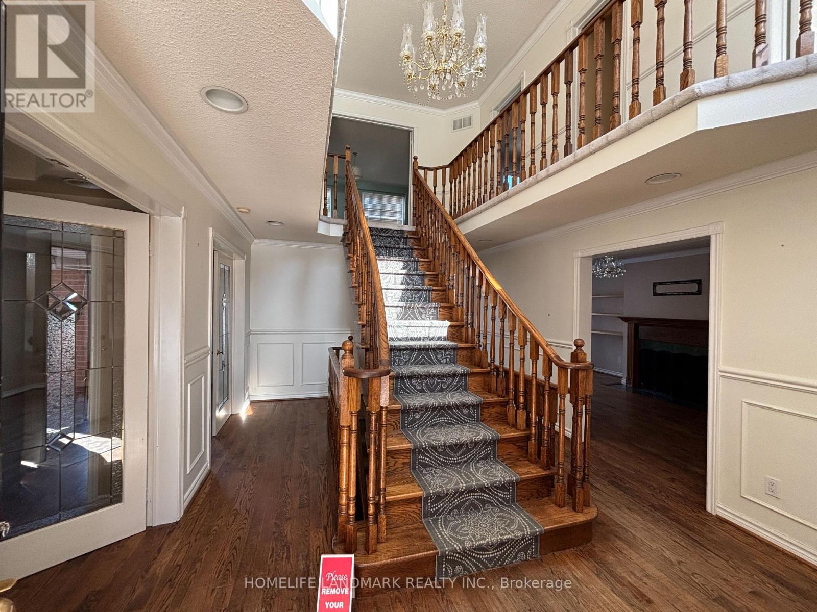 A staircase with a wooden banister and a chandelier above it.