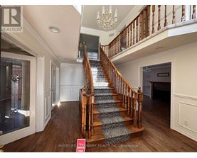 A staircase with a wooden banister and a chandelier above it.