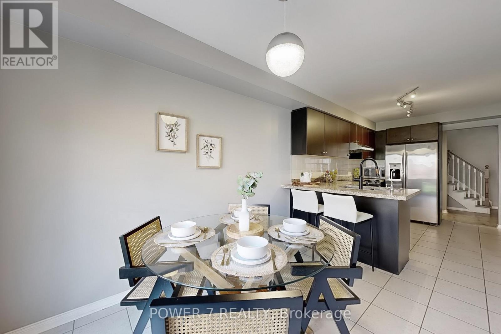 A dining area with a table set for two and a kitchen in the background.