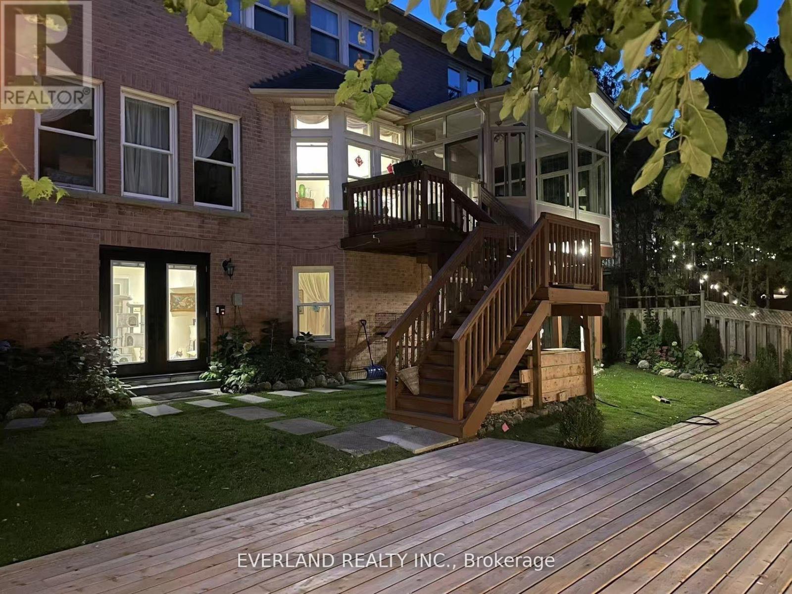 A house with a wooden deck and a tree branch in the foreground.