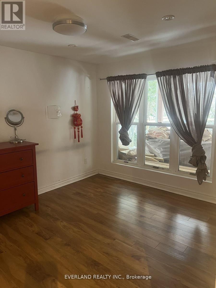 A room with a wooden floor and a window with curtains.