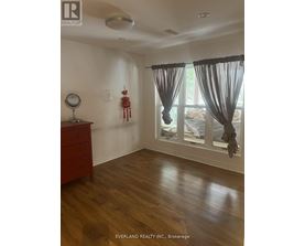 A room with a wooden floor and a window with curtains.