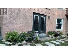 A brick house with a black door and a window with flowers in front.