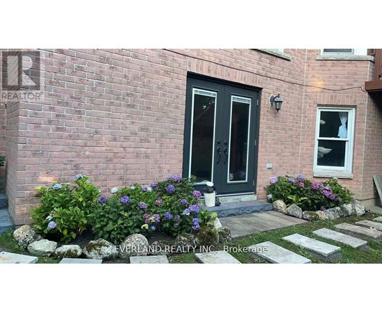 A brick house with a black door and a window with flowers in front.