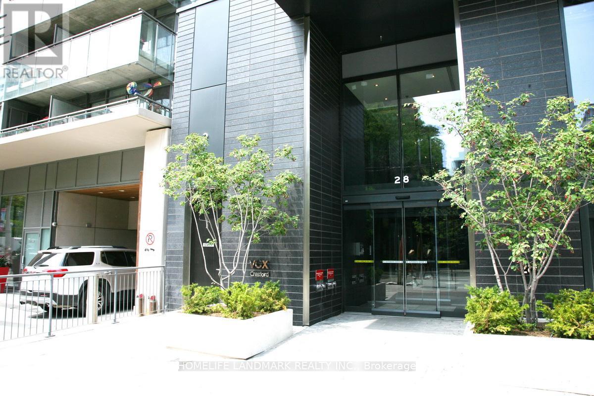 A modern building with glass doors and windows, and a tree in front.