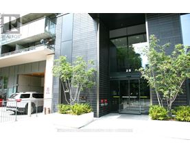 A modern building with glass doors and windows, and a tree in front.