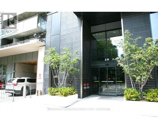 A modern building with glass doors and windows, and a tree in front.
