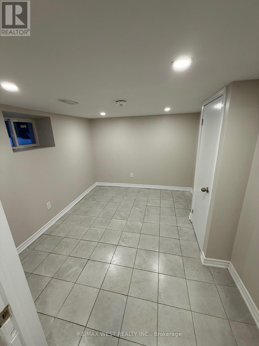 A spacious room with tile flooring and a brokerage sign.