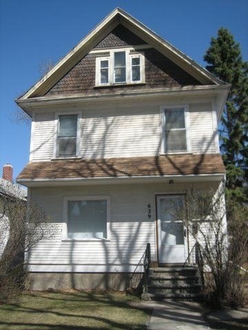 A two-story house with a white exterior and a brown roof.