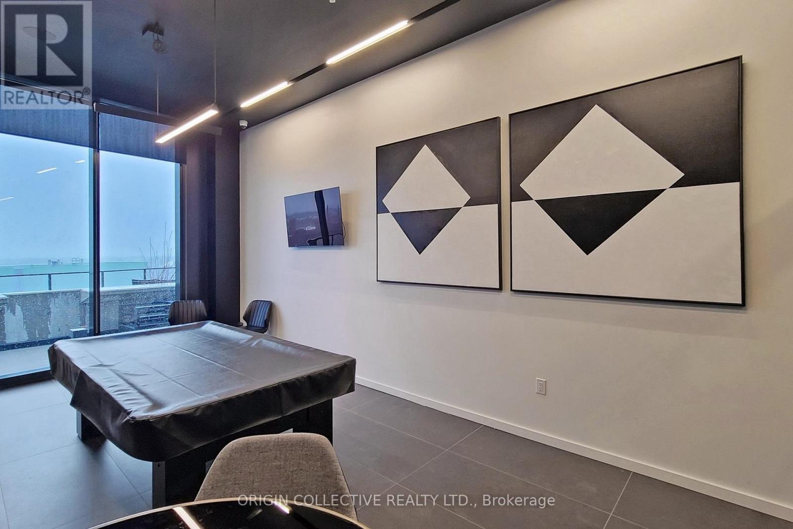 A modern dining room with a large table and three black and white geometric paintings on the wall.
