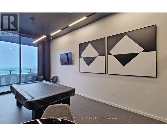 A modern dining room with a large table and three black and white geometric paintings on the wall.