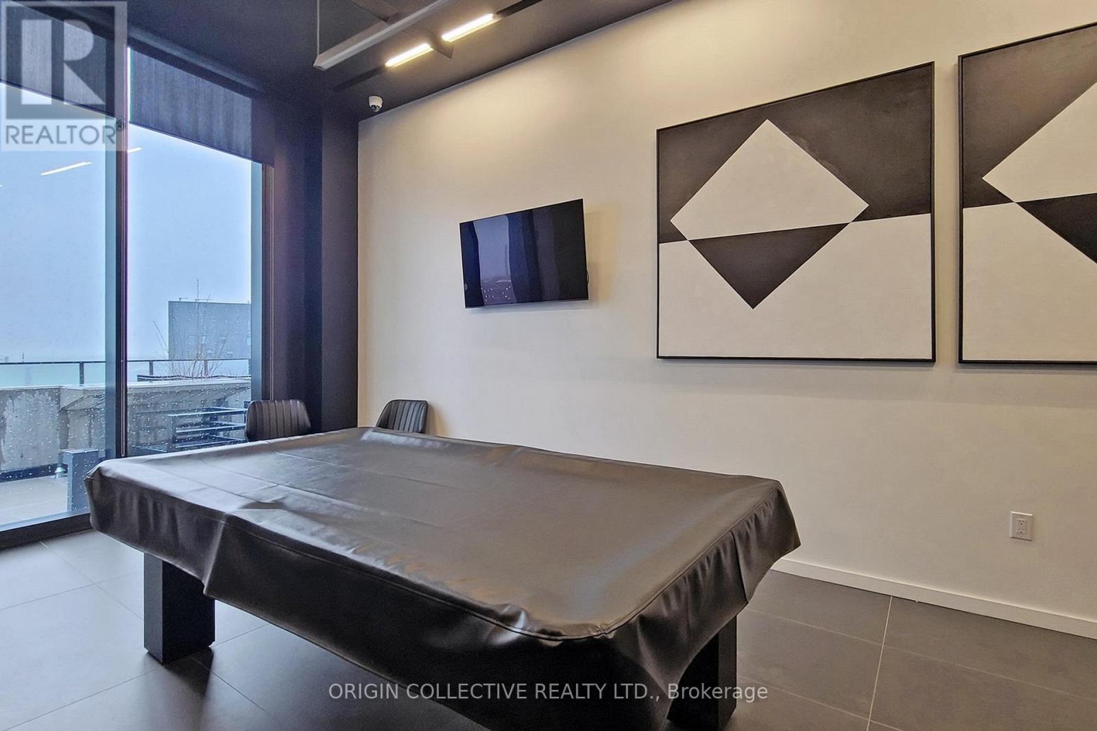 A bedroom with a bed, a flat screen TV and two geometric artworks on the wall.