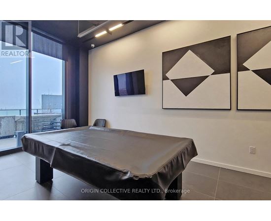 A bedroom with a bed, a flat screen TV and two geometric artworks on the wall.