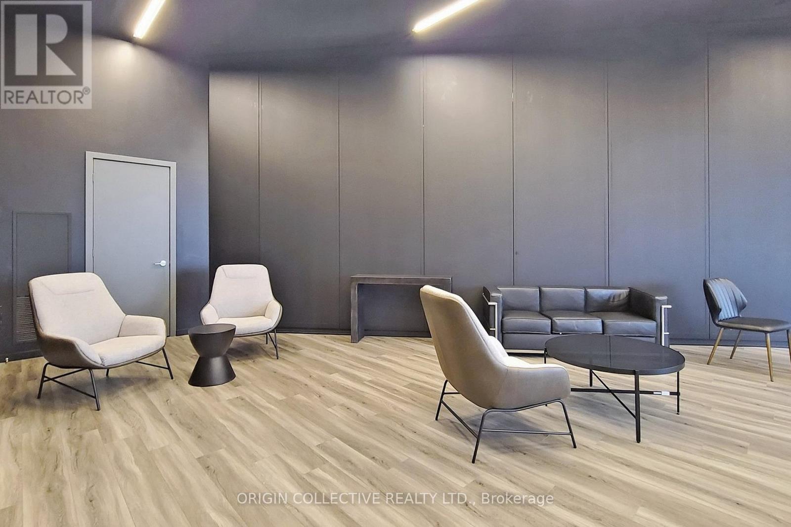 A modern living room with a grey couch, white chairs, and a black coffee table.