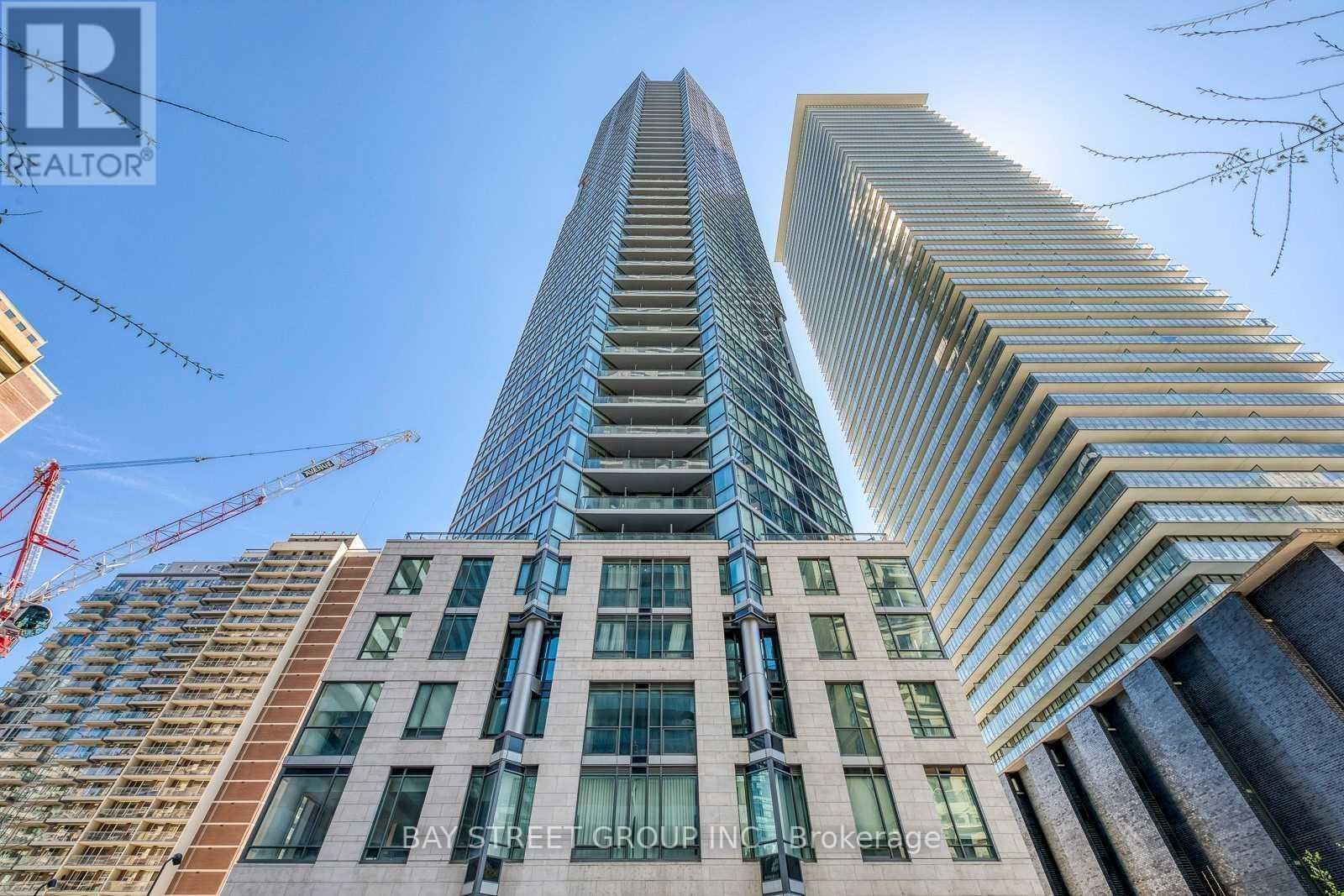 A tall building with a glass facade stands next to a shorter building with a brick facade.