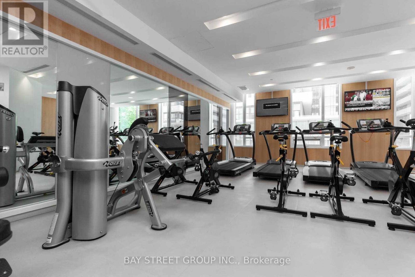 A gym with a row of treadmilers and a row of stationary bikes.
