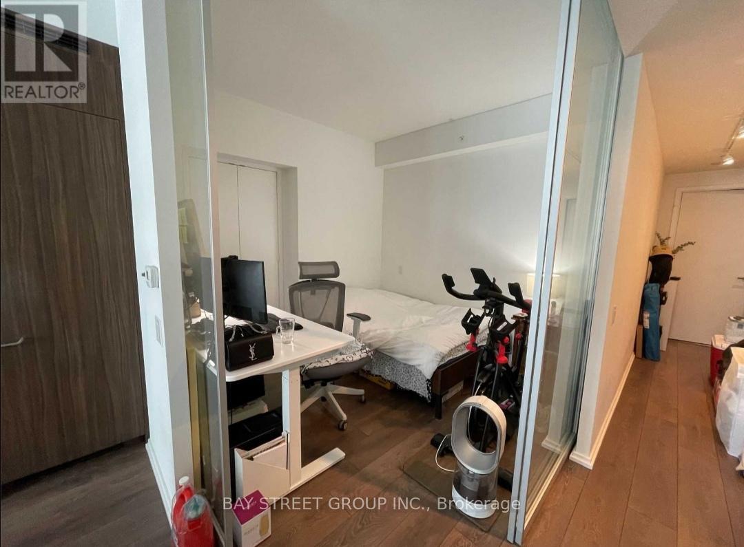 A bedroom with a bed, desk, and exercise equipment.