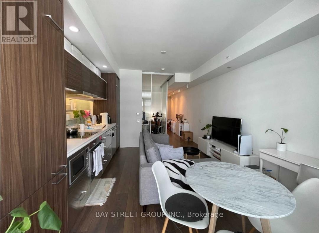 A modern living room with a kitchen area in the background.