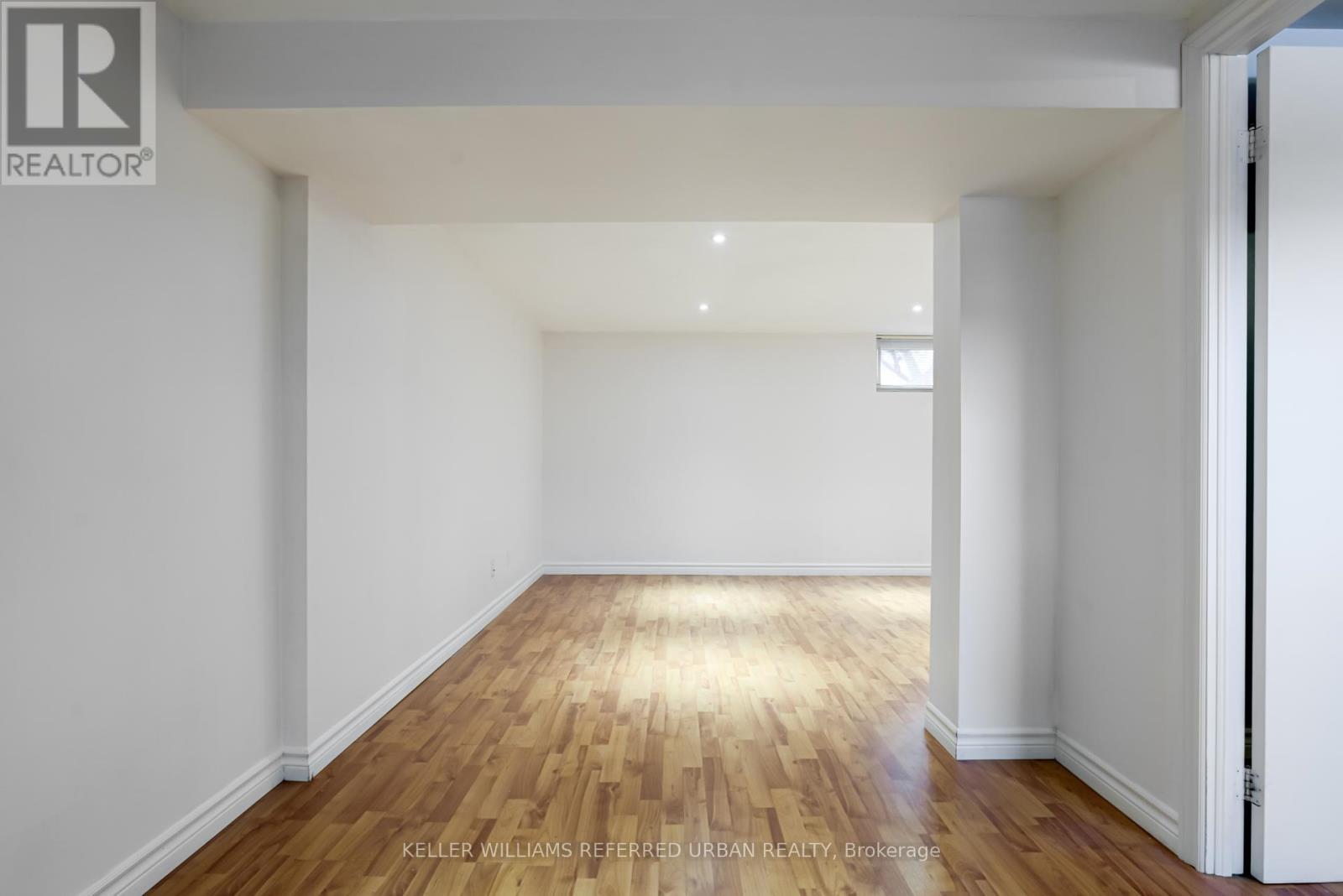 A spacious room with wooden flooring and white walls.