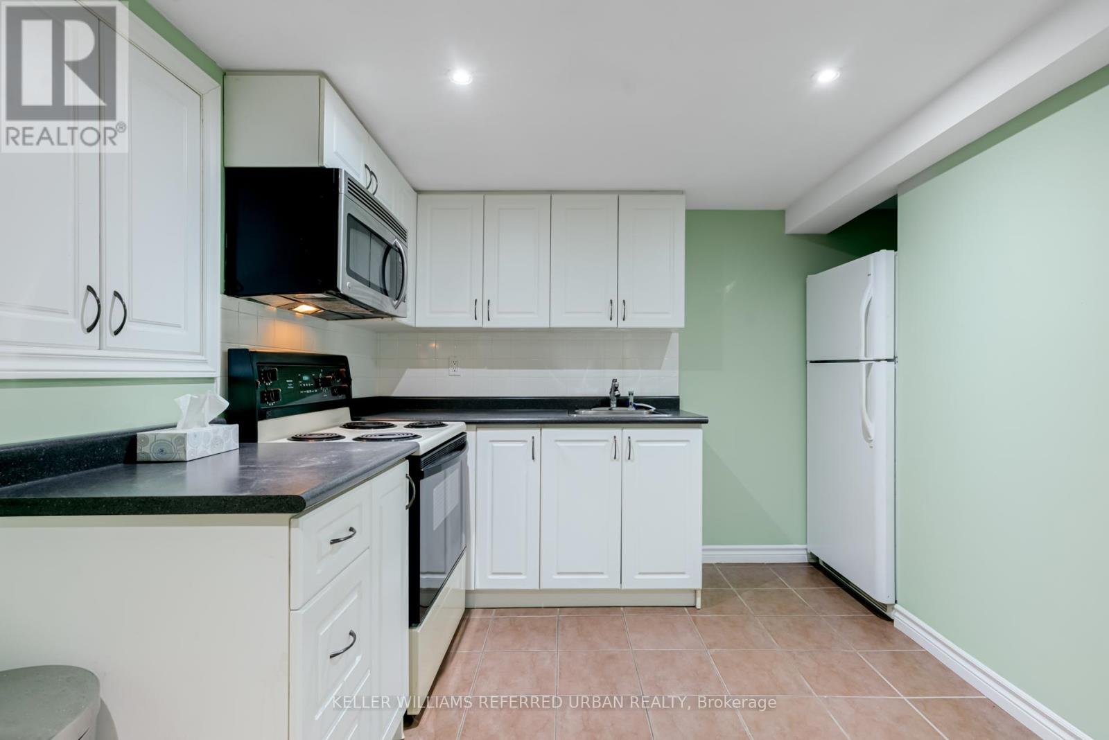 A kitchen with white cabinets and a black countertop.