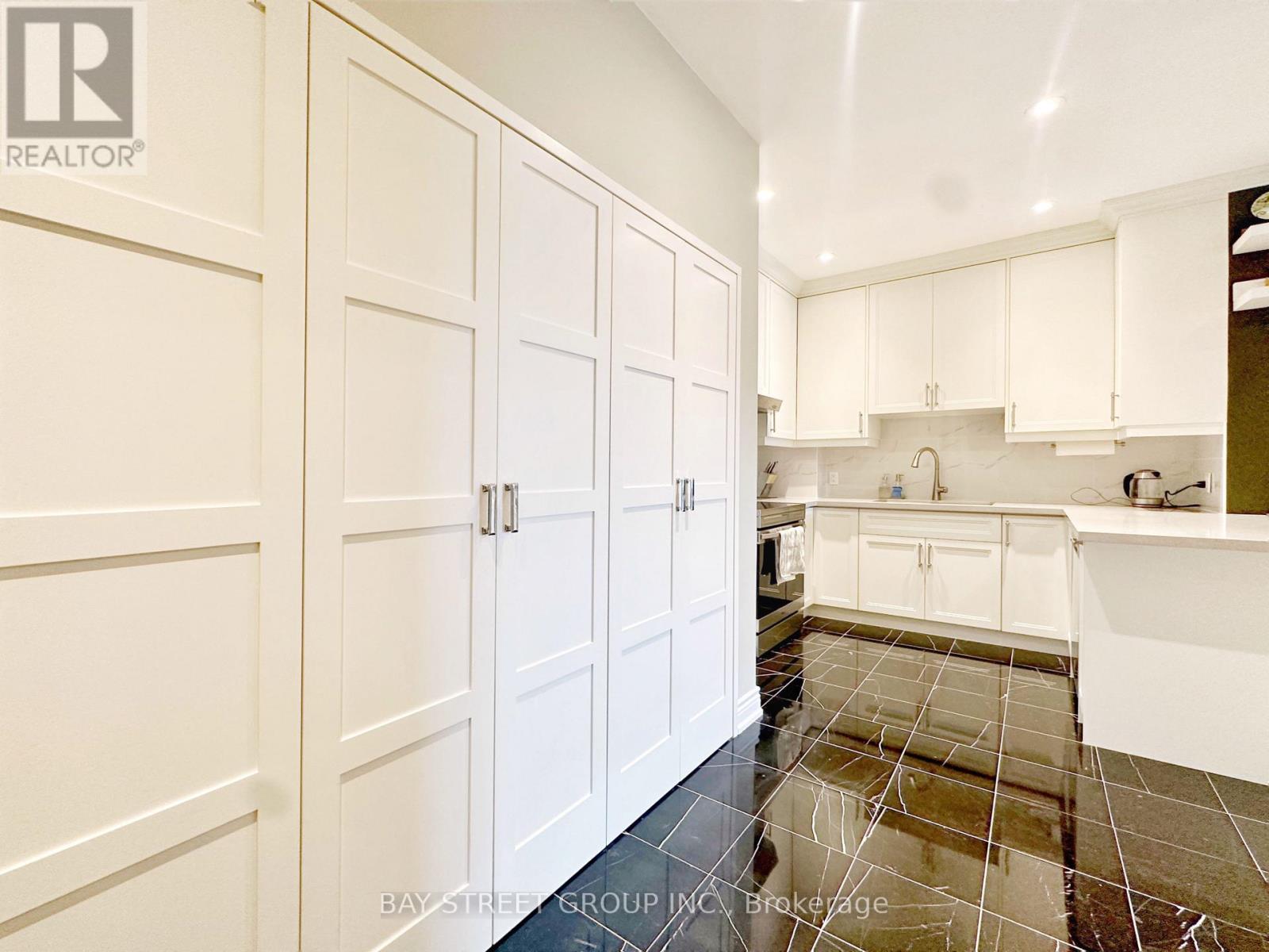 A kitchen with white cabinets and a tile floor.
