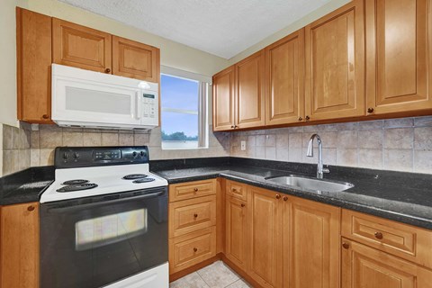A kitchen with wooden cabinets and a black countertop.
