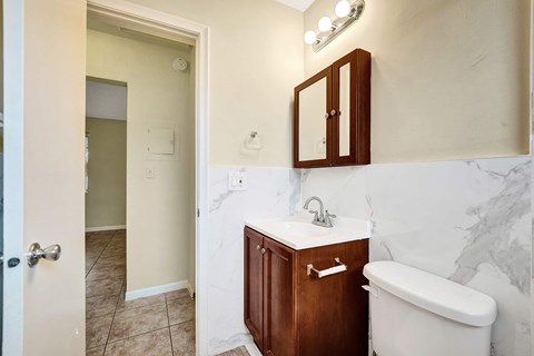 A white sink with a brown cabinet and a white bathtub in a bathroom.