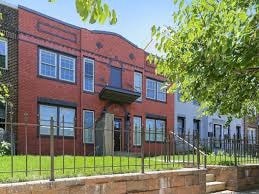 A red brick building with a black fence in front.
