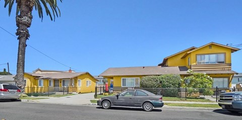 A yellow house with a grey car parked in front.
