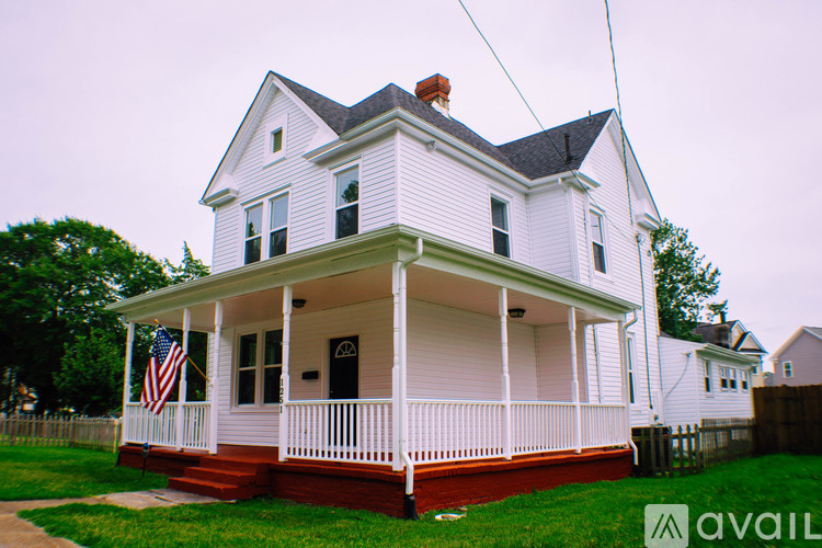 A white house with a red door and a balcony.