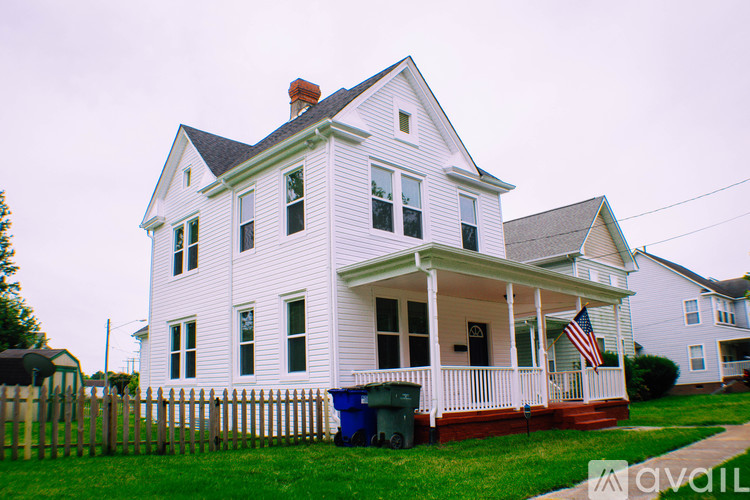 A white house with a black roof and a flag on the porch.