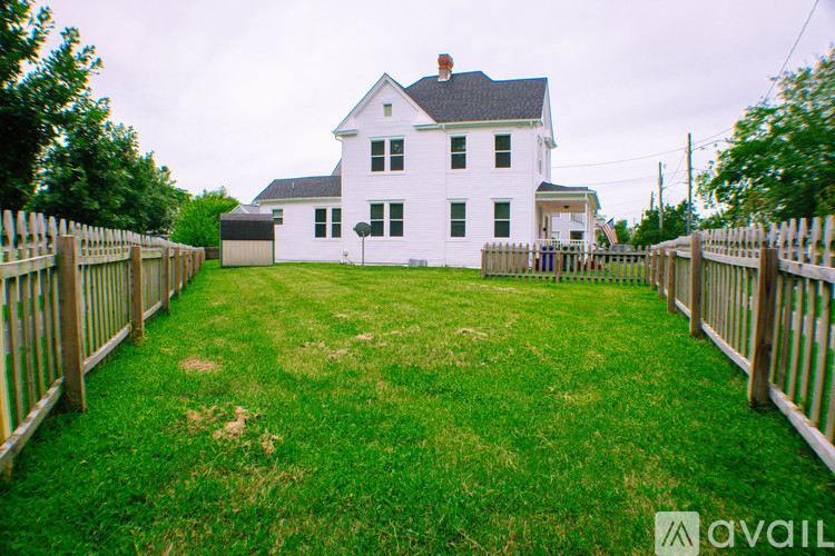 A white house with a black roof and a fence in front of it.