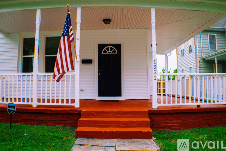 A house with a black front door and an American flag hanging on the porch.