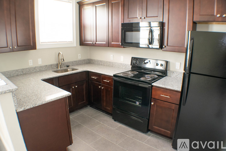 A kitchen with brown cabinets and black appliances.