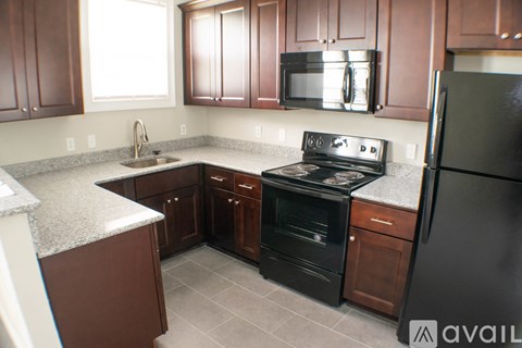 A kitchen with brown cabinets and black appliances.