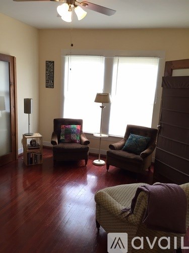 A living room with two chairs and a table with a lamp on it.