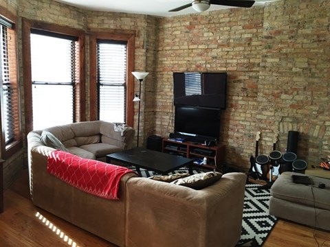 A living room with a brown couch and a black television.