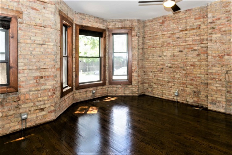 A room with a brick wall and wooden floors.