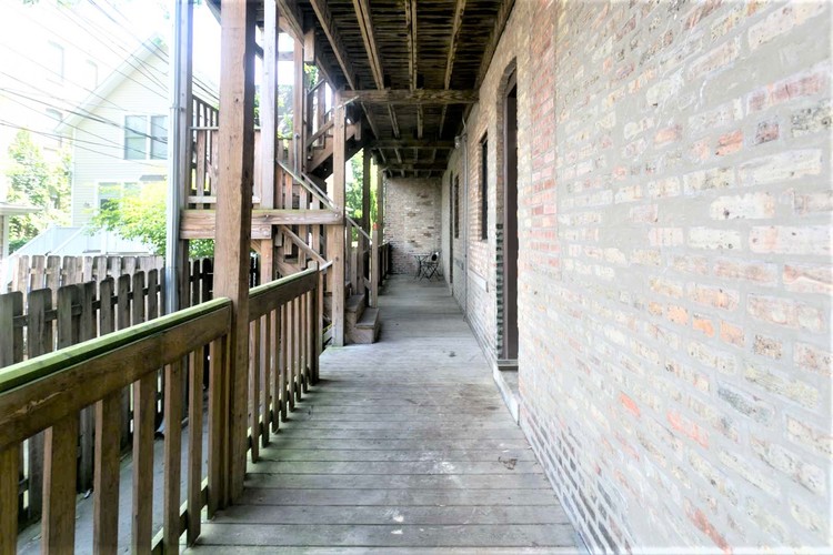 A long wooden walkway with brick walls on either side.