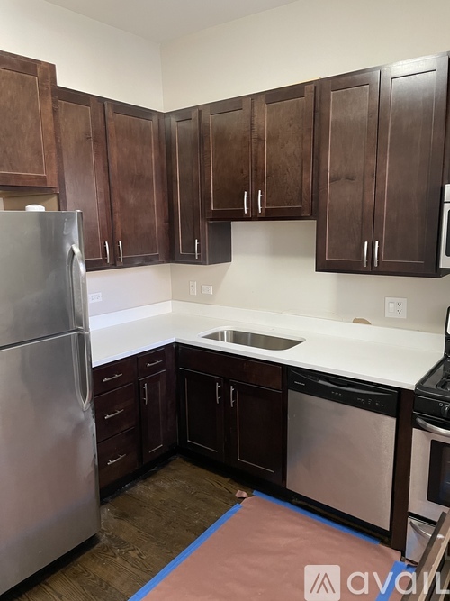 A kitchen with brown cabinets and a stainless steel refrigerator.