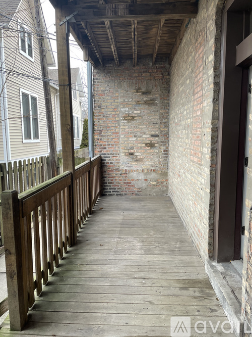 A wooden walkway leads to a door in a brick wall.