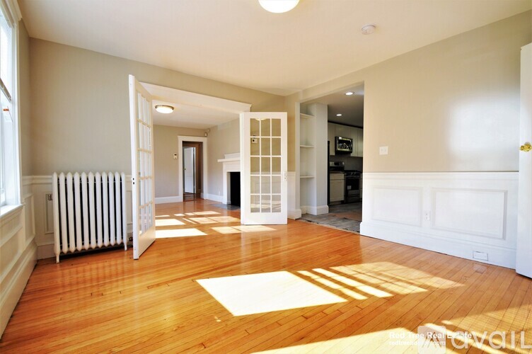 A spacious room with wooden floors and white walls.