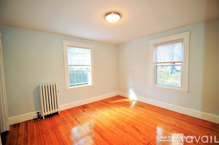 A room with a red floor and two windows.