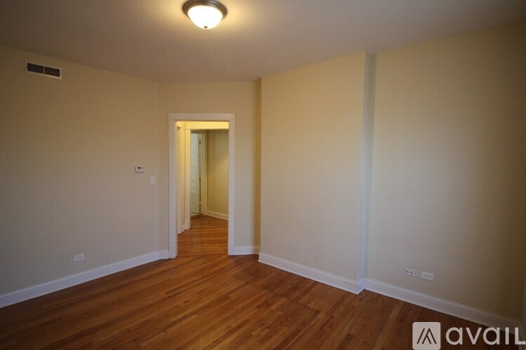 A room with wooden floors and a doorway leading to another room.