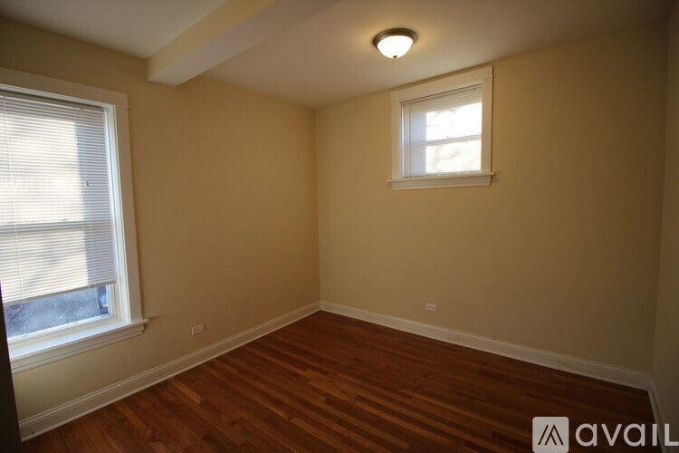 A room with wooden floors and a window with blinds.