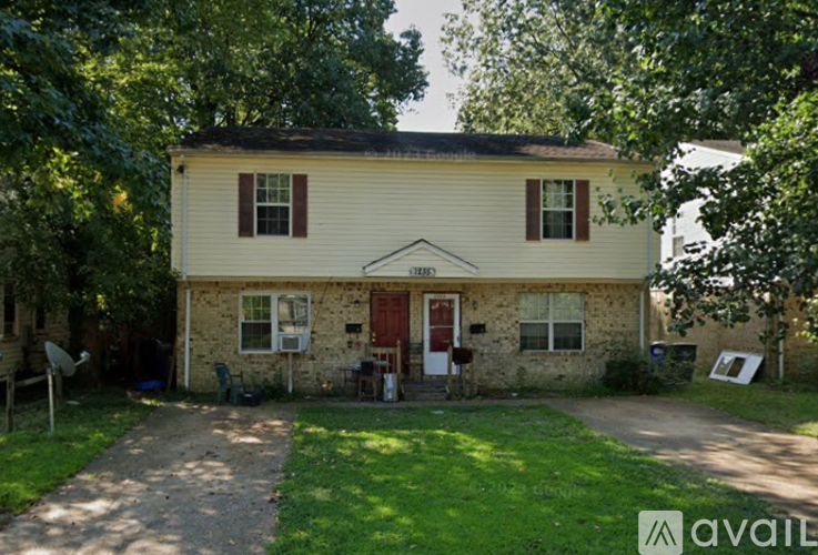 A two-story house with a red door and a sign that says "available" in the front yard.