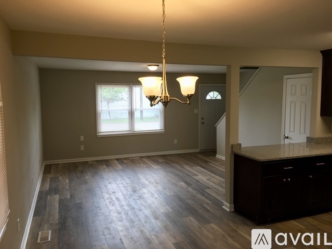 A room with wooden flooring and a chandelier hanging from the ceiling.