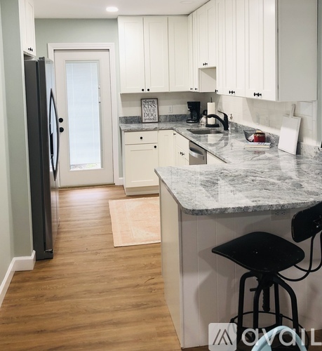 A kitchen with a marble counter top and white cabinets.