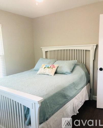 A white bed with a blue comforter and two pillows with a floral design.